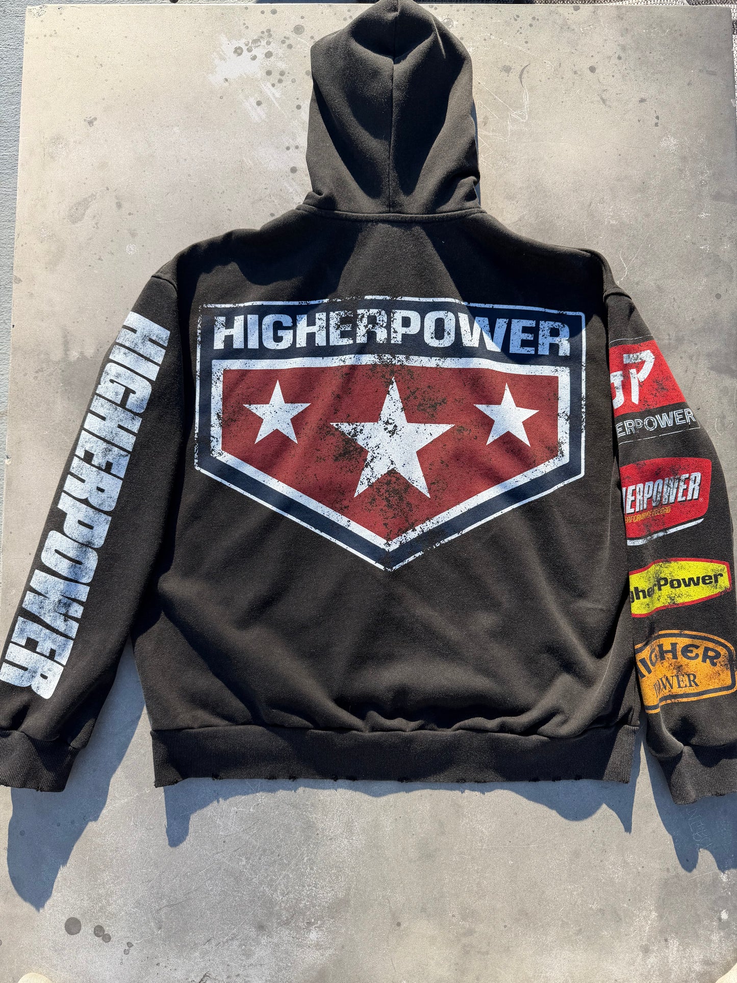 Black hoodie with 'Higher Power' logo and text on a concrete surface