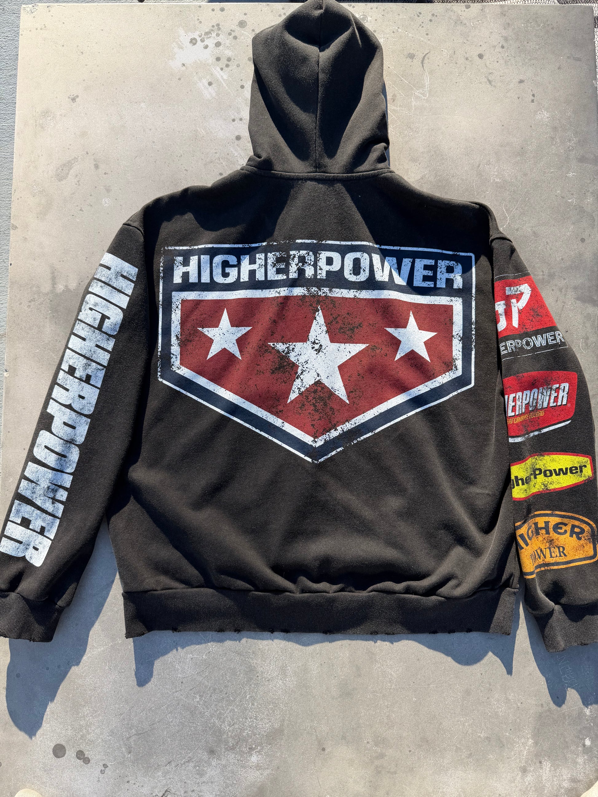 Black hoodie with 'Higher Power' logo and text on a concrete surface