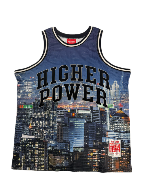 A blue mesh basketball jersey with 'HIGHER POWER' printed in black arched text across the front, featuring a city skyline graphic and a red Mitchell & Ness neck label.