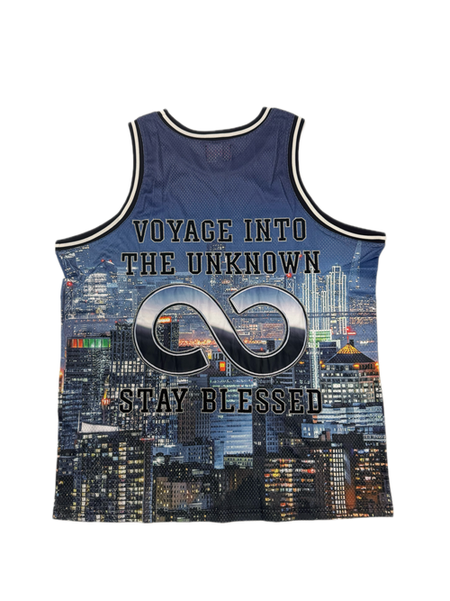 A sleeveless athletic tank top with a navy blue and black city skyline print, featuring the text 'VOYAGE INTO THE UNKNOWN' and 'STAY BLESSED' with a large infinity symbol on the front.
